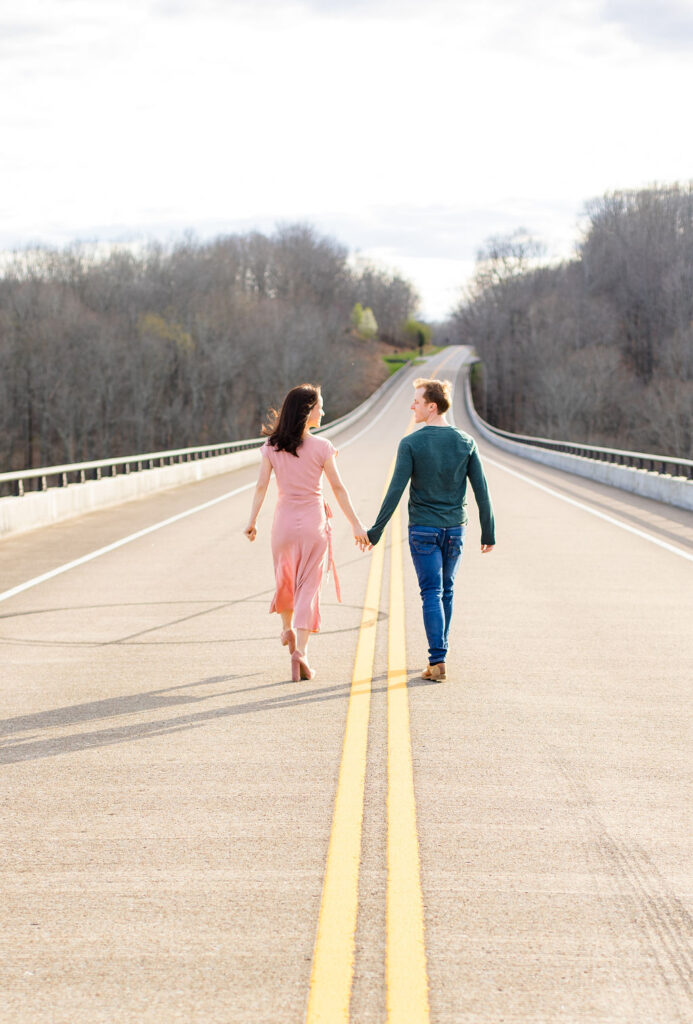 Two people walking along Natchez Trace Parkway Bride, hand in hand while looking towards each other 