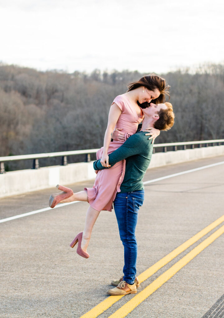 Man lifting his fiancé in the middle of the bridge in Nashville, TN during their engagement session