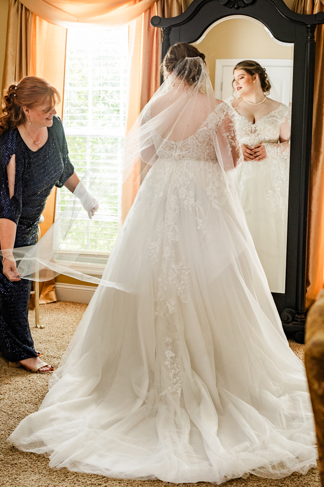 Mother of the bride fluffing her daughter's veil in the bridal suite at Annabella at Cedar Glen.