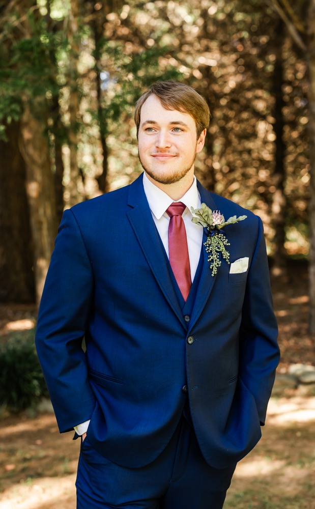 Groom all dressed up in a navy suit on his wedding day, gazing off into the distance