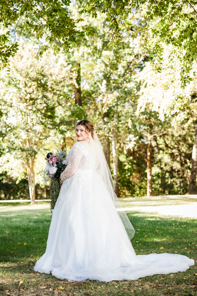 Bride peering over her left shoulder as she showcases the back of her wedding dress.