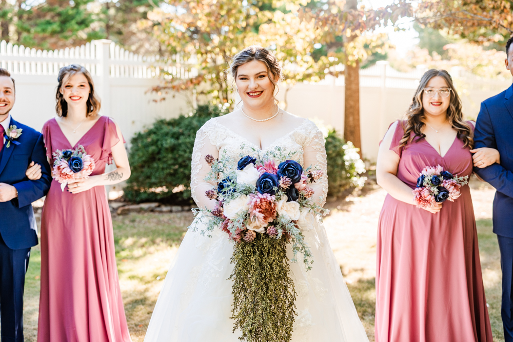 Bride with her bridesmen and bridesmaids a few feet behind her.