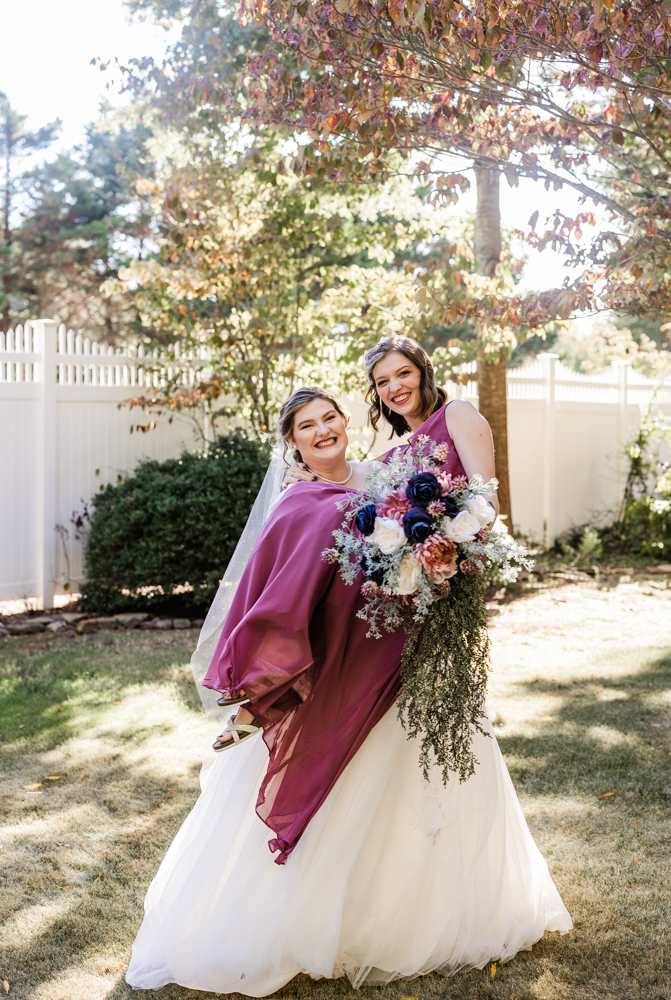 Bride holding her sister in her arms to recreate a picture they took when they were younger.