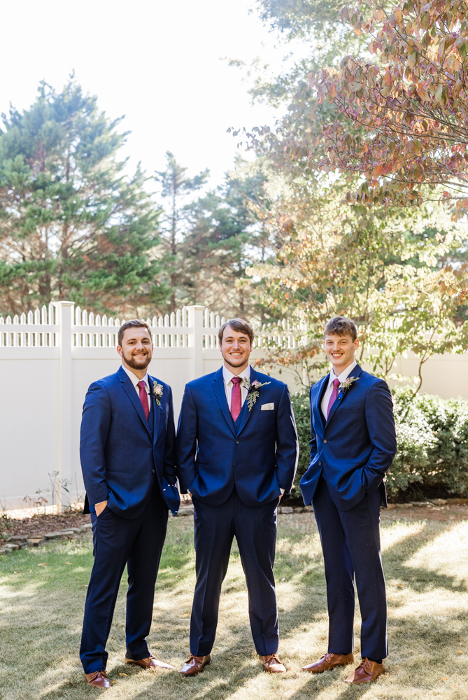 Groom with his two groomsmen all dressed in navy suits with pink ties.