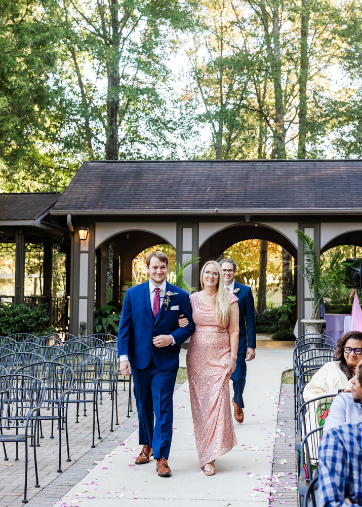 Groom escorting his mom down the aisle in the outdoor ceremony space at Annabella at Cedar Glen.