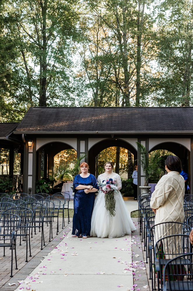 Bride, escorted by her mom, walking down the aisle in the outdoor ceremony space at Annabella at Cedar Glen.