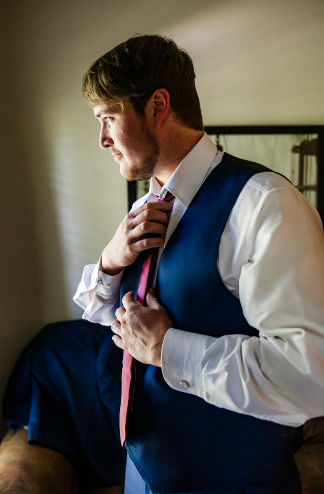 Groom putting on his tie in the groom's suite at Annabella at Cedar Glen.