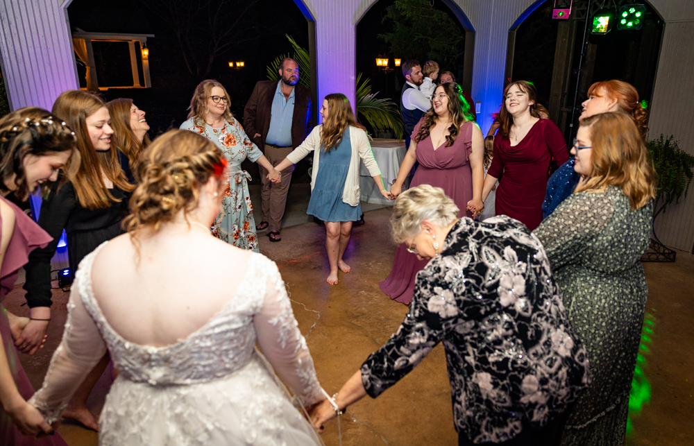 Guests holding hands in a circle as they dance during a wedding reception at Annabella at Cedar Glen.