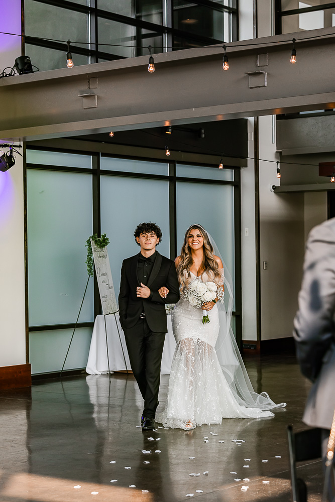 The Bridge Building bride walking down the aisle during an indoor wedding ceremony