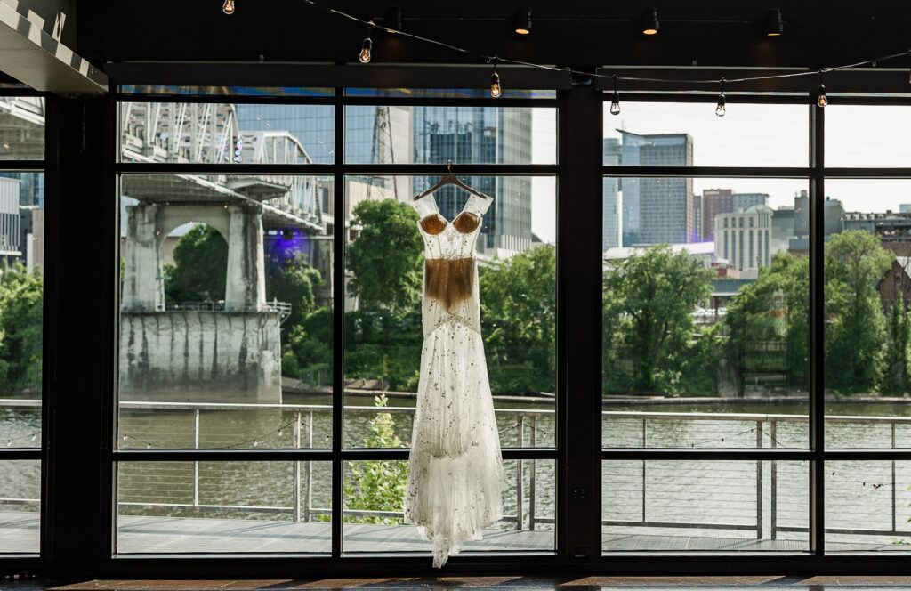 The Bridge Building dress hanging in the window with the city in the background