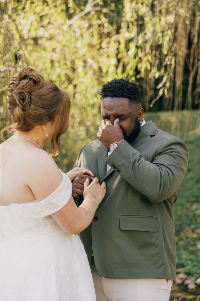 Emotional groom wiping away tears during the first look with his bride.