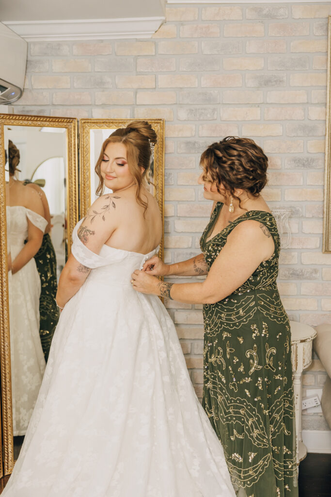 Bride's mother helping her put on her wedding dress