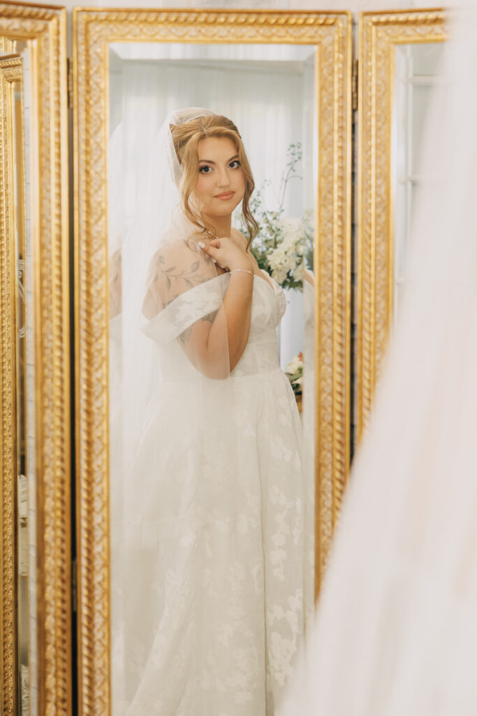 Reflection of the bride in a mirror, showing her wedding dress and veil