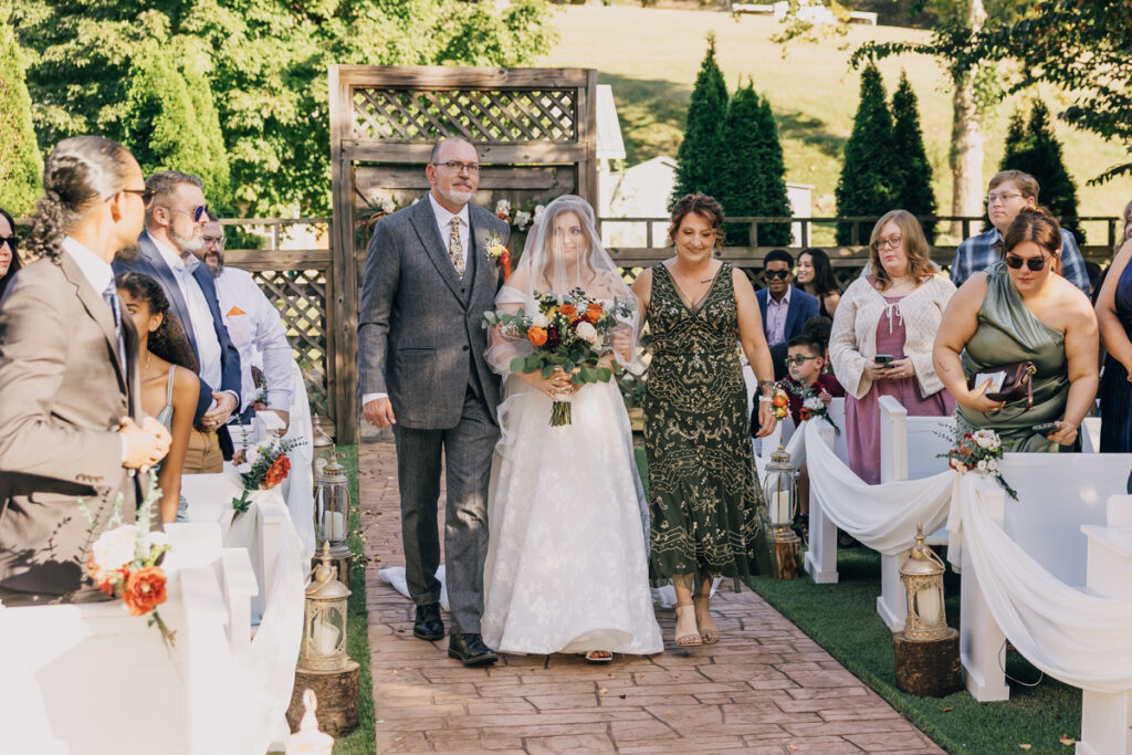 Bride walking down the aisle escorted by her mom and dad
