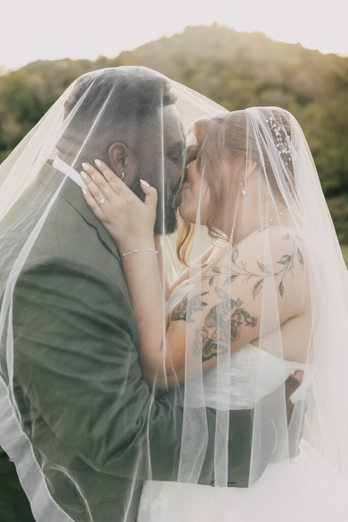 Bride and groom sharing a kiss underneath the bride's veil