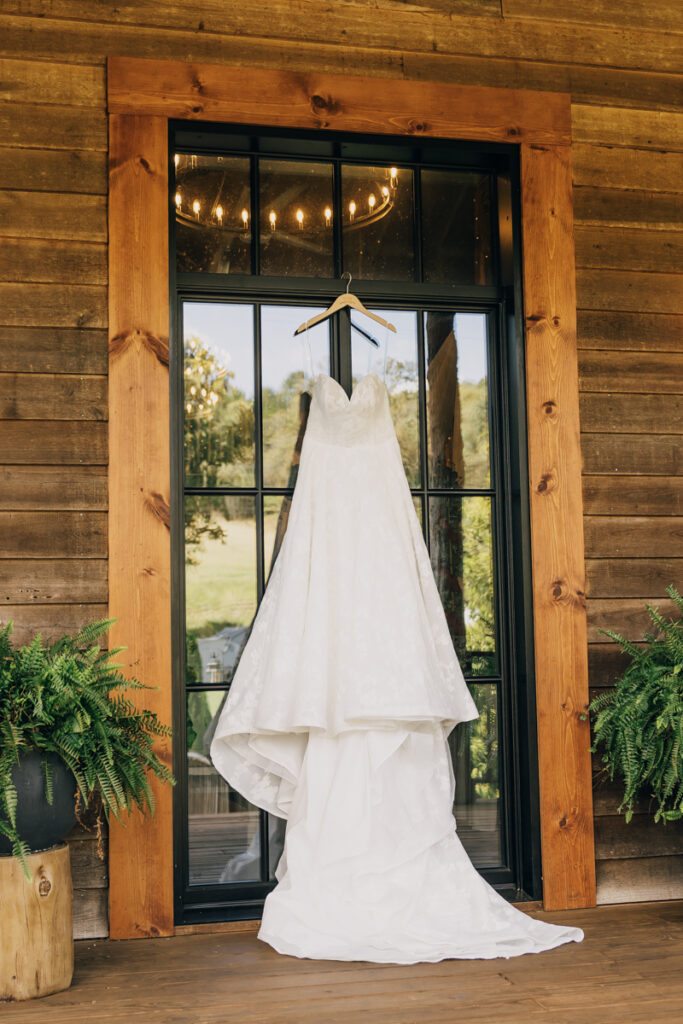 Wedding dress hanging from door at rustic elegance event venue