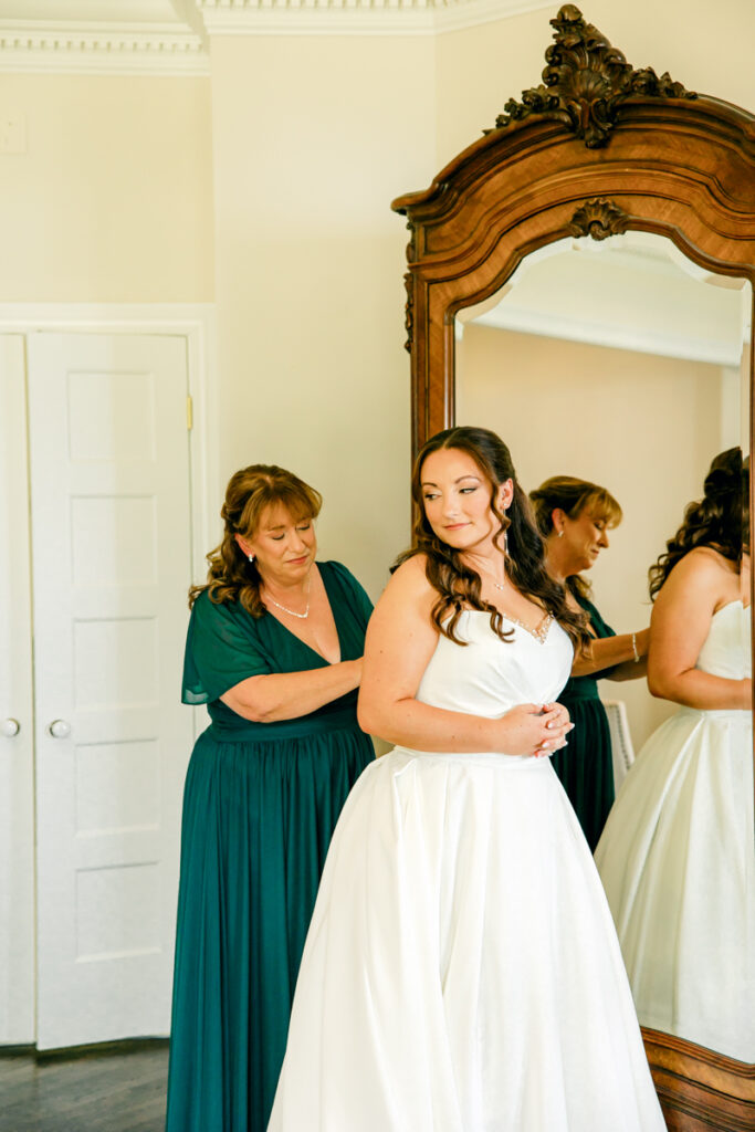 Bride’s mother helping her into her wedding dress.
