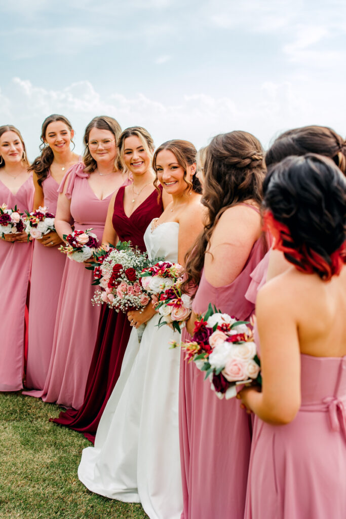 Bridesmaids all smiling towards the bride.