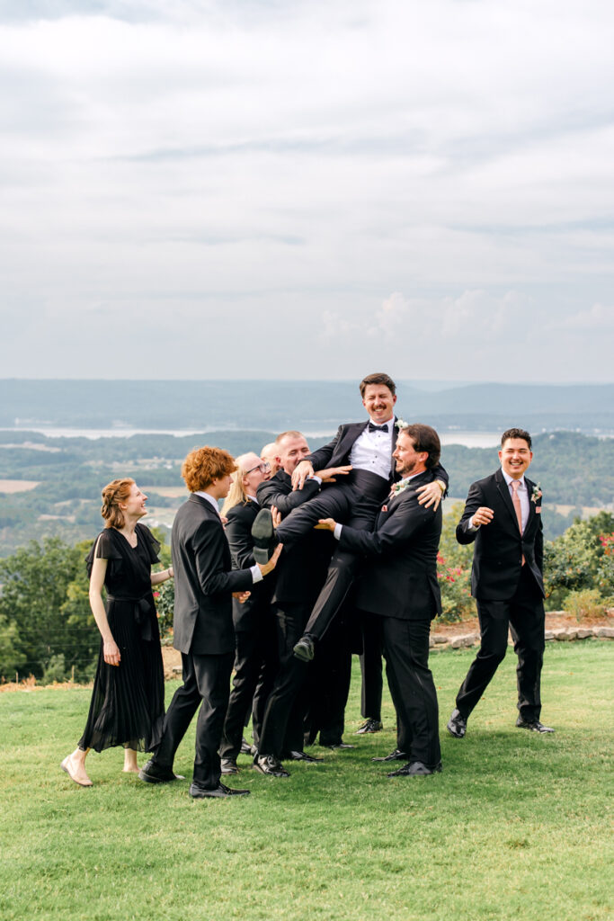 Groom being lifted up by his groomsmen.