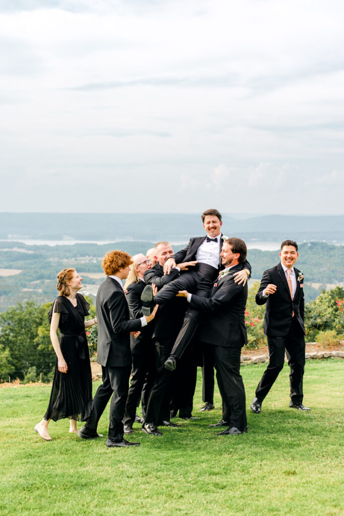 Groomsmen playfully lifting the groom at Stone Haven wedding venue