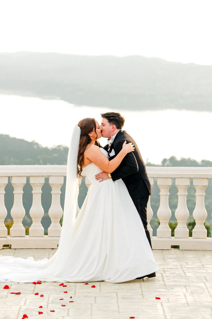 Bride and groom sharing their first kiss as the sun breaks through the clouds during Stone Haven ceremony.