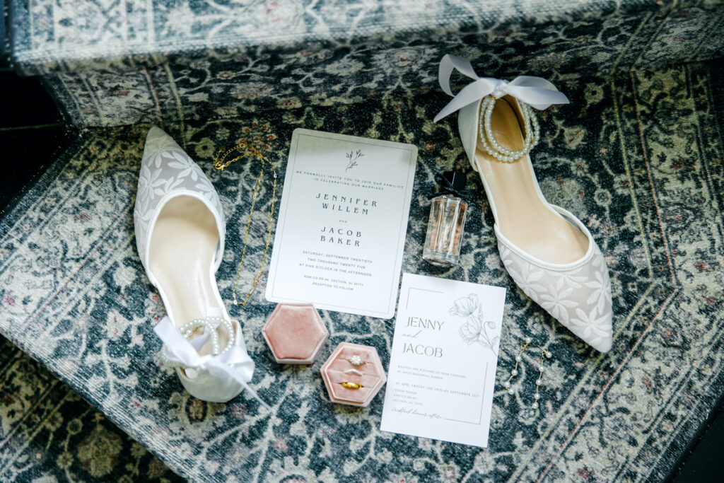 Flatlay of bridal details including rings, shoes, and invitation suite at the French-inspired Rock House at Stone Haven.