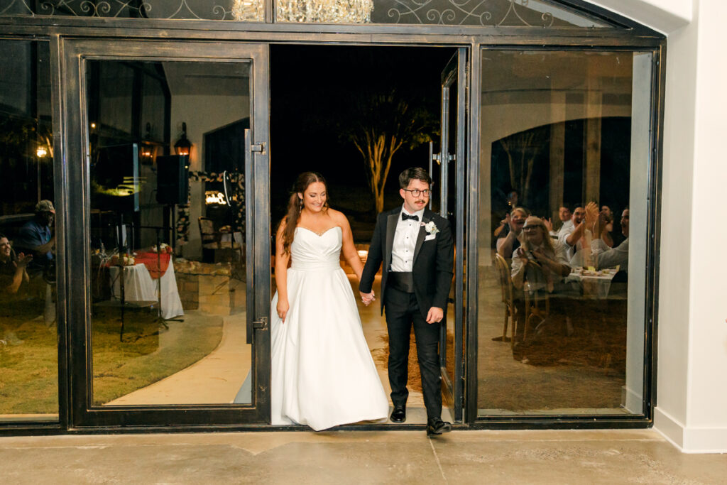 Bride and groom walking into their Stone Haven reception as guests cheer. 