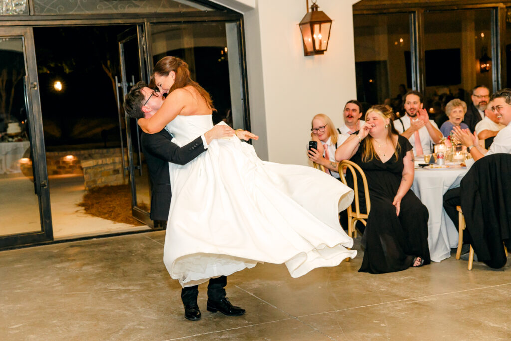 Groom lifting and twirling his bride during their first dance.