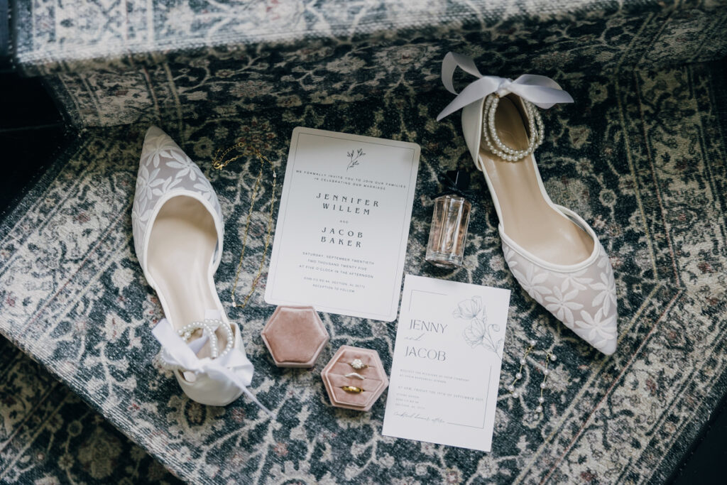 Flatlay of bridal details including rings, shoes, and invitation suite at the French-inspired Rock House at Stone Haven.