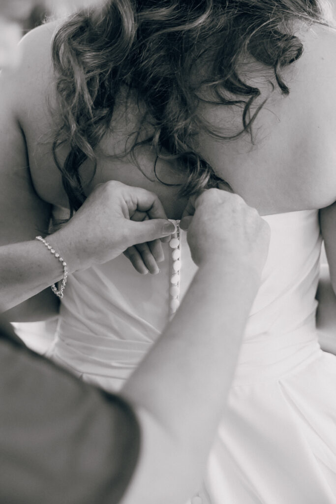 Bride getting her dress buttoned by her mother at Stone Haven wedding venue