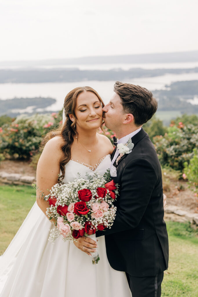 Groom kissing his bride on the cheek at Stone Haven wedding in Section, AL