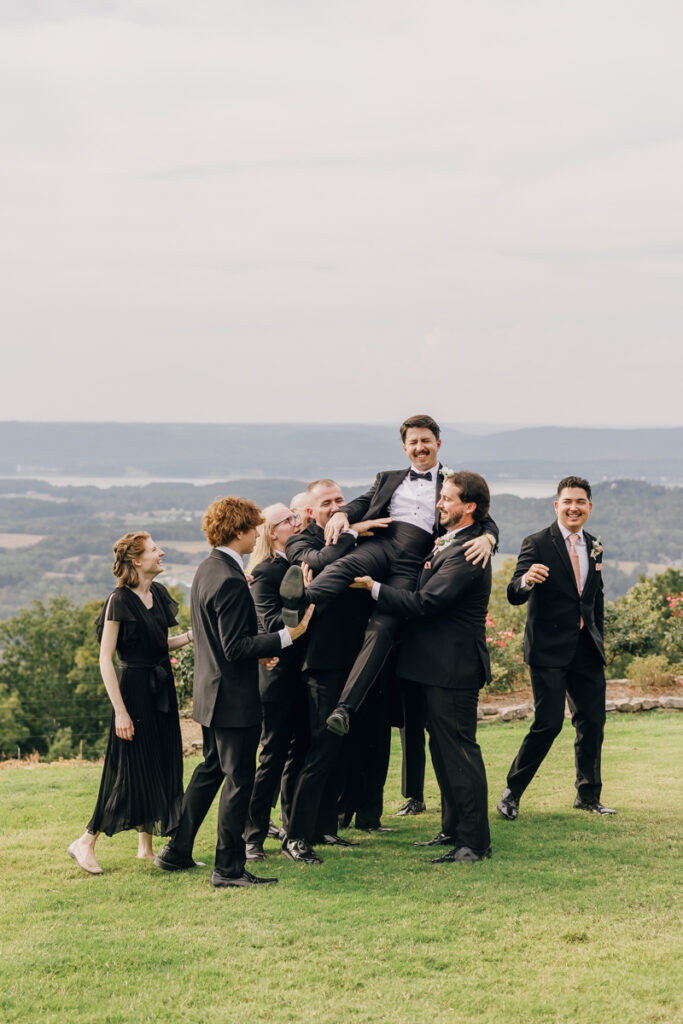 Groomsmen playfully lifting the groom at Stone Haven wedding venue