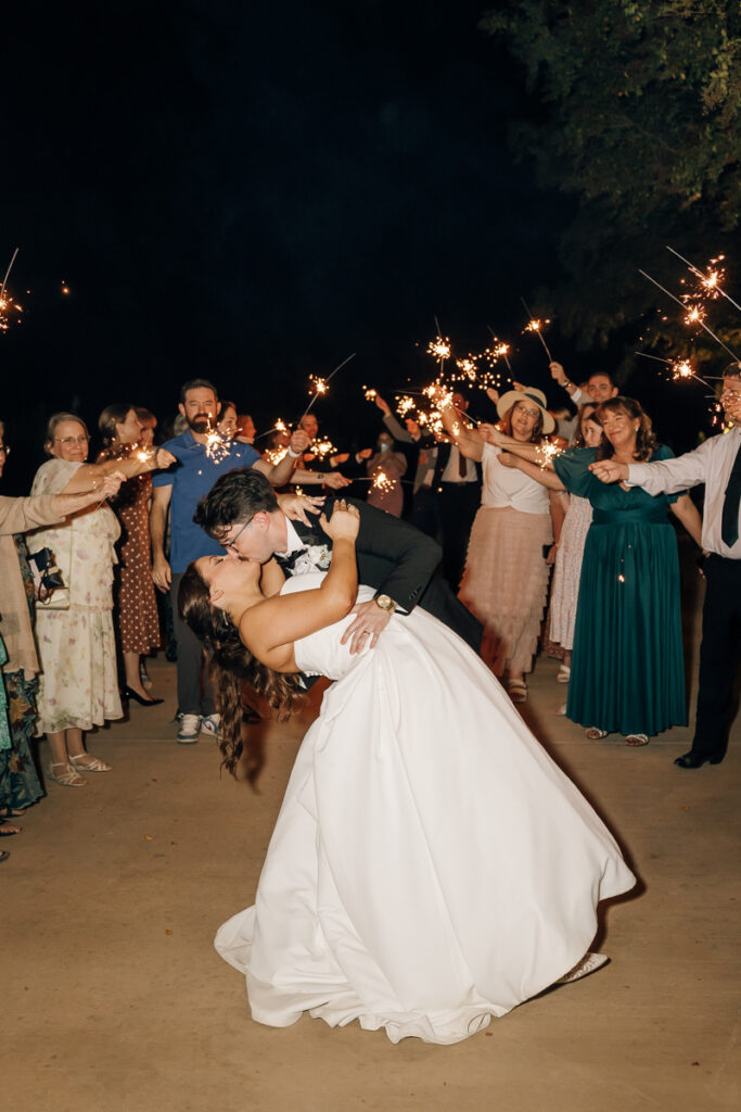 Bride and groom dipping and kissing during their sparkler exit at Stone Haven in Section, Alabama.