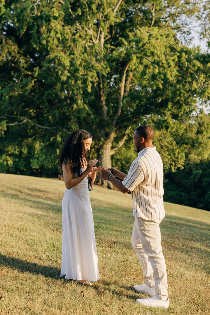 Man placing engagement ring onto fiancée’s finger.