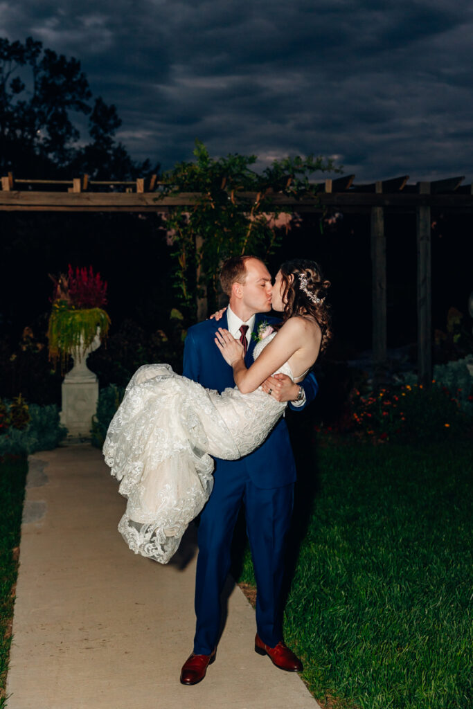 Groom carrying his bride on their wedding day at Tayvin Gardens.