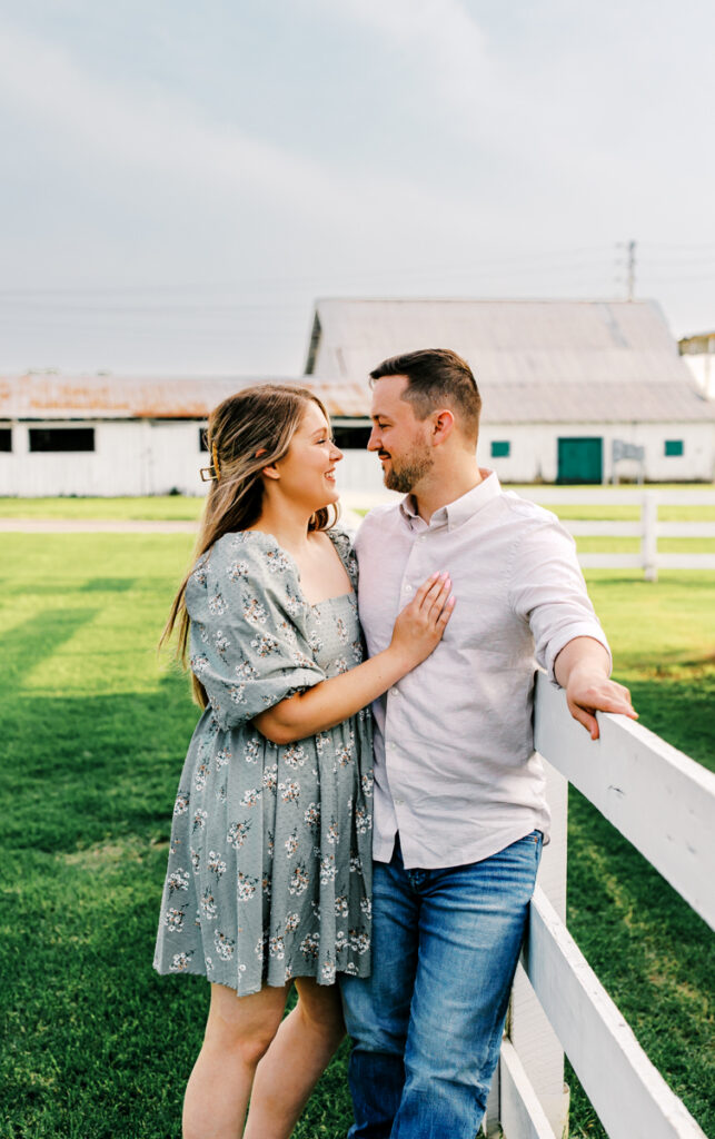 Man leaning against a fence while embracing his fiancée