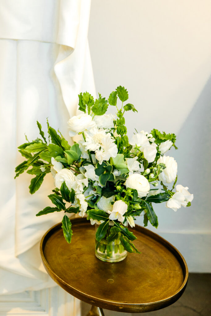 Green and white floral arrangement in a vase on a table in the bridal suite at Saint Elle wedding venue