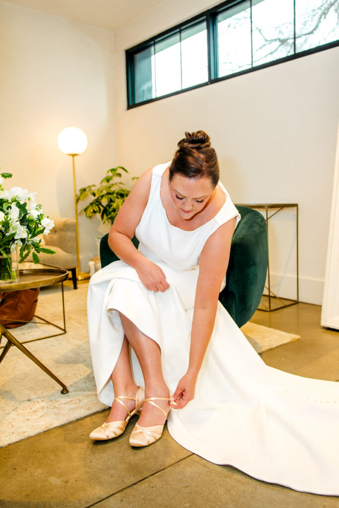 Bride puts on wedding shoes on in the bridal suite at Saint Elle