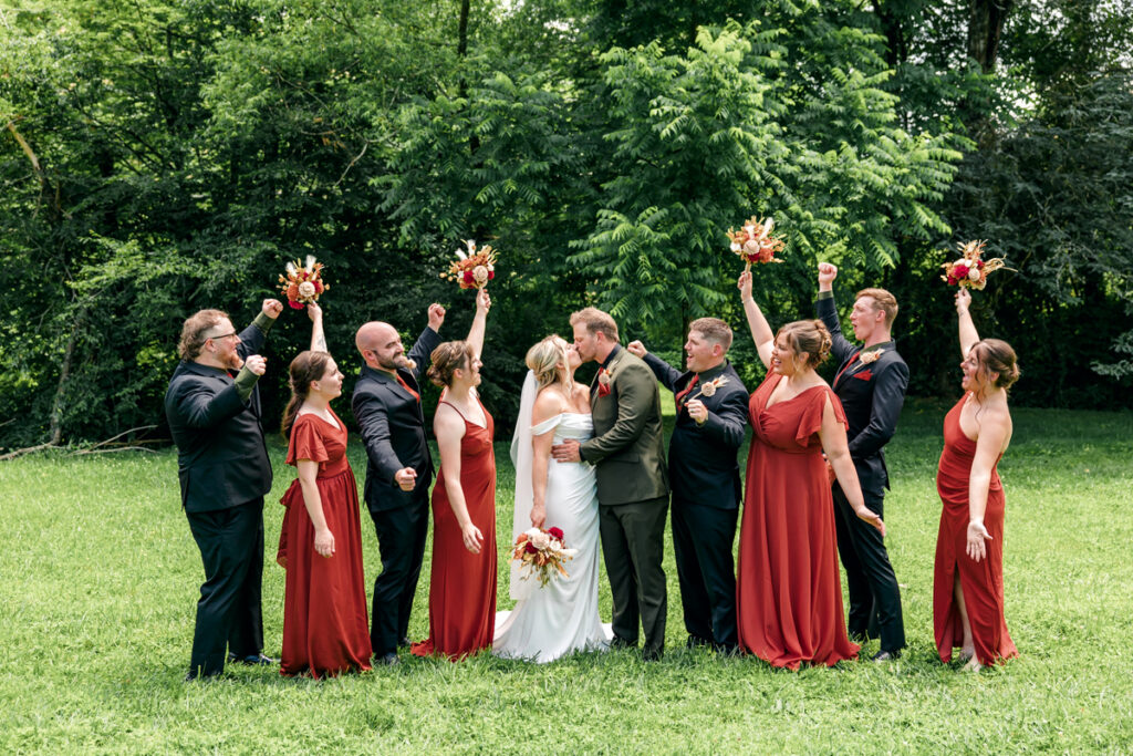 Wedding party cheers on the bride and groom as they share a kiss