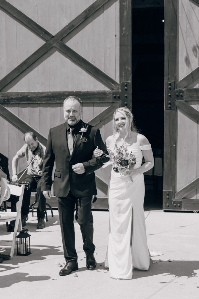 Black and white photo of the bride walking down the aisle with her dad