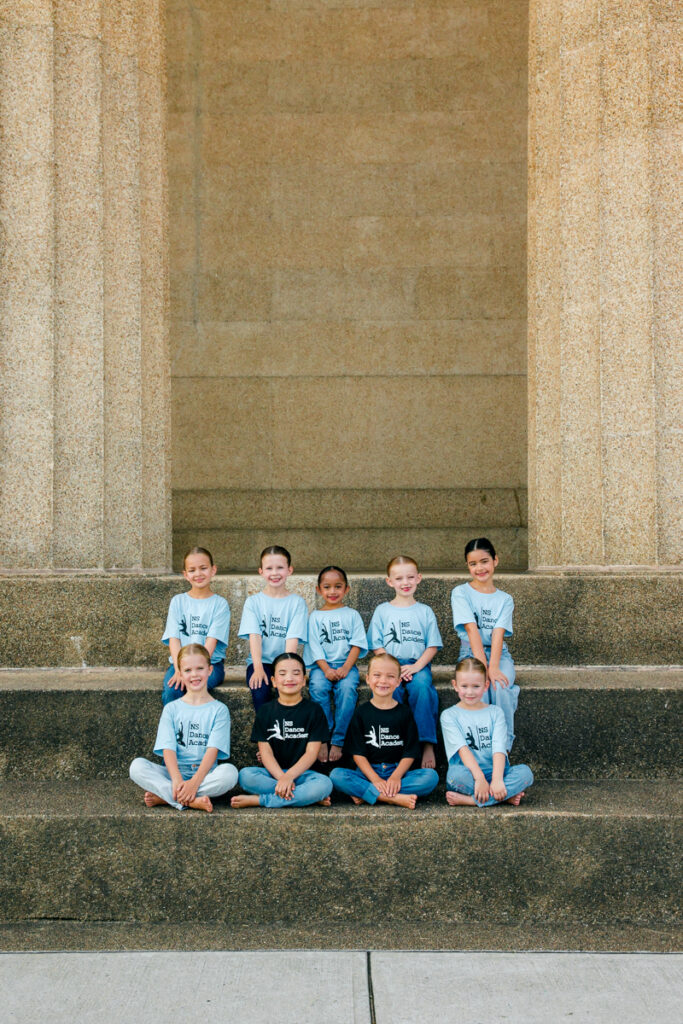 Young dancers sitting on large steps, smiling