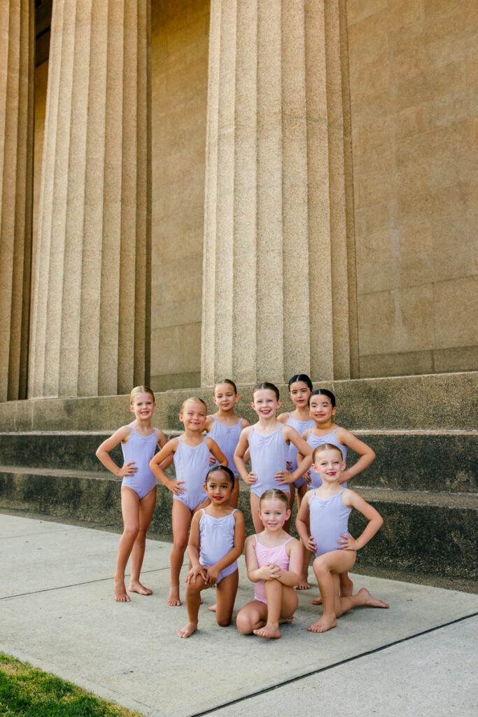 Young dancers in purple leotards posing during an outdoor dance portrait session.