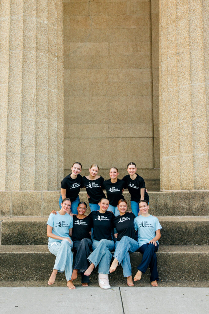 NS Dance Academy students sitting on The Parthenon steps in Nashville, wearing t-shirts and jeans for their 2025 dance photo session.