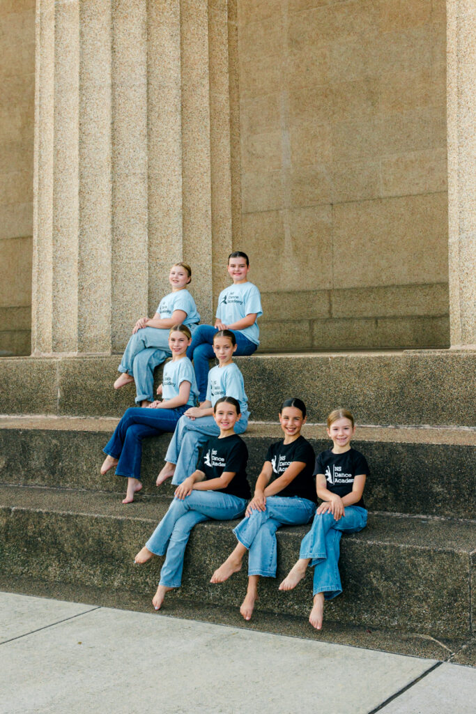 Girls siting cross-legged on large outdoor steps.
