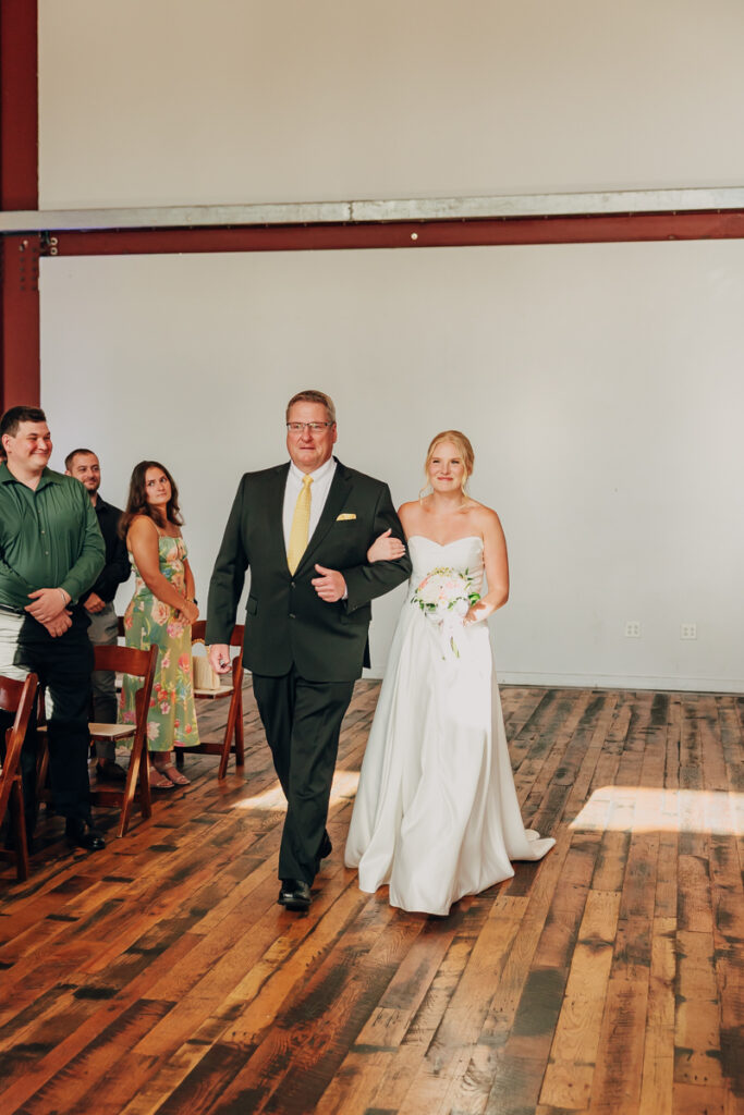 Bride walking down the aisle with her dad at The Reserve at Fat Bottom Brewery