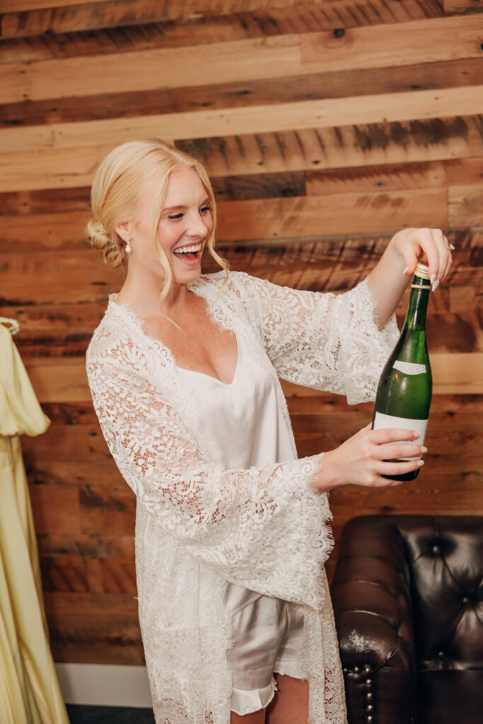 Bride opening a bottle of champagne