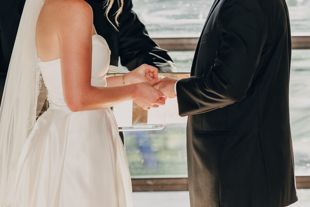 Bride placing the groom’s wedding band on his finger