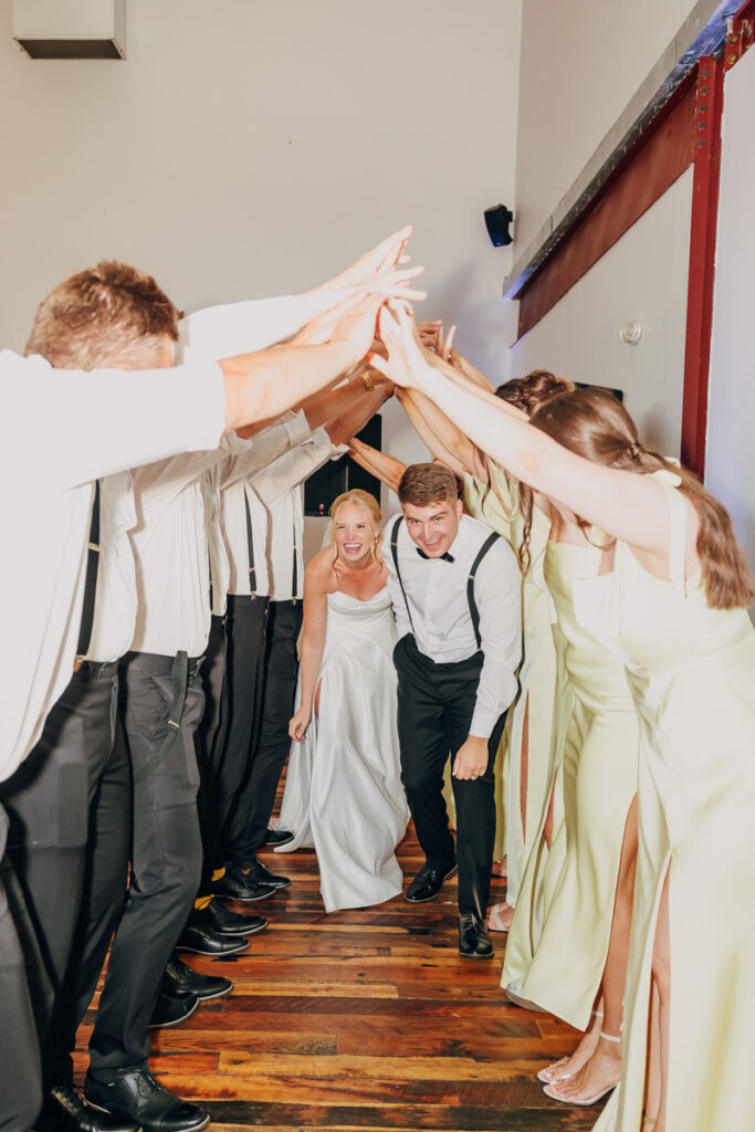Bride and groom running through a human tunnel to enter their wedding reception