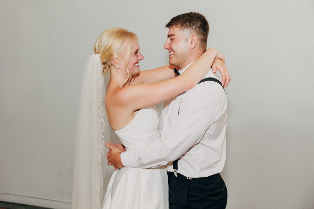 Bride and groom smiling at each other during their first dance.