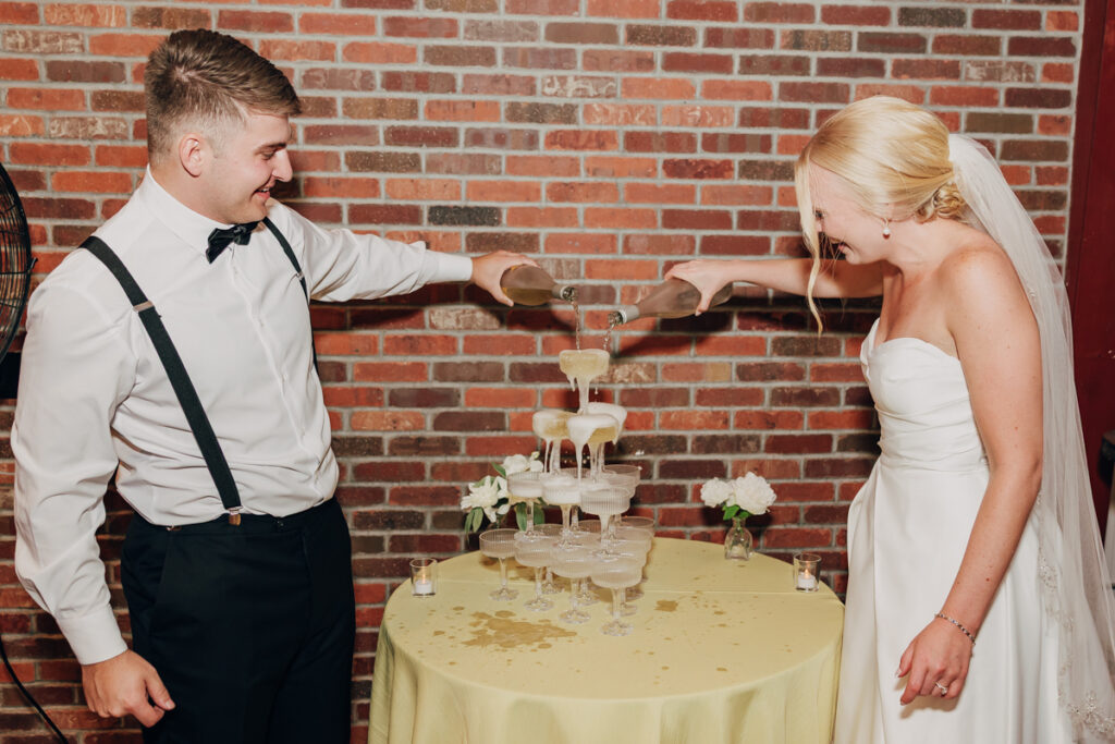 Bride and groom pouring champagne into a champagne tower at their Nashville wedding reception.